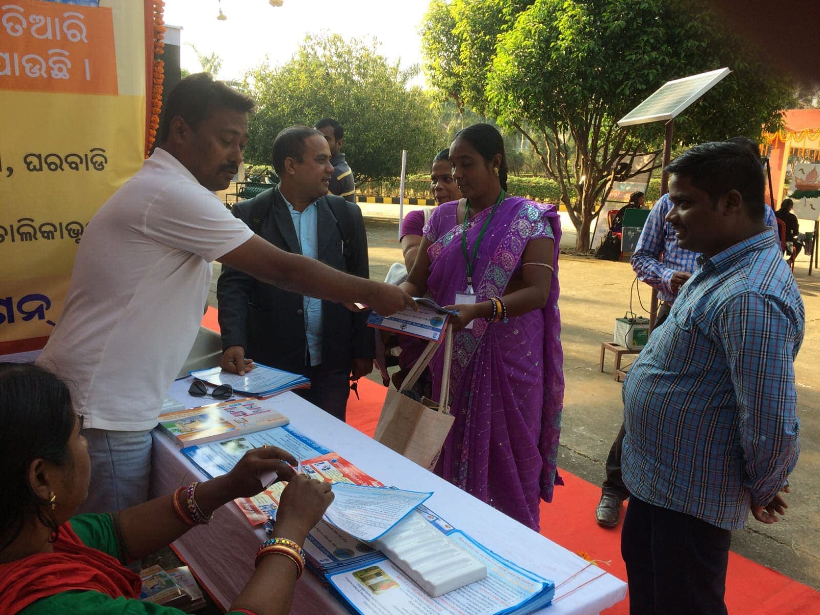 An IIES field worker handing sanitation programme material to a visitor
