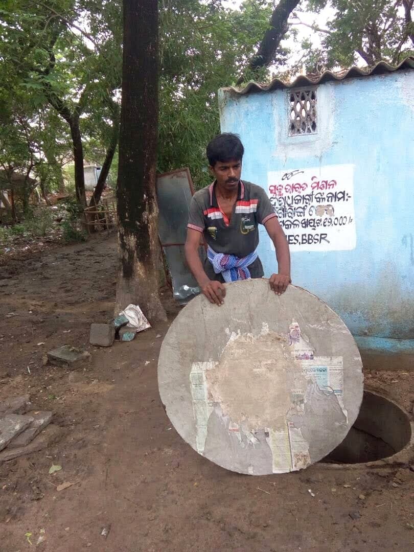 An IIES field worker installing a twin-pit latrine cover